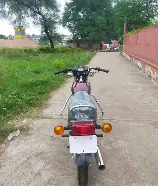 A classic 1990 Yamaha RX100 motorcycle parked on a street with a rider showcasing its vintage charm.