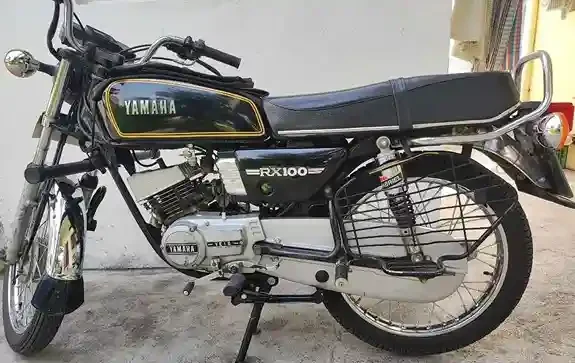 A side view of the 1990 Yamaha RX100 featuring a rider, highlighting its stylish design and lightweight construction.