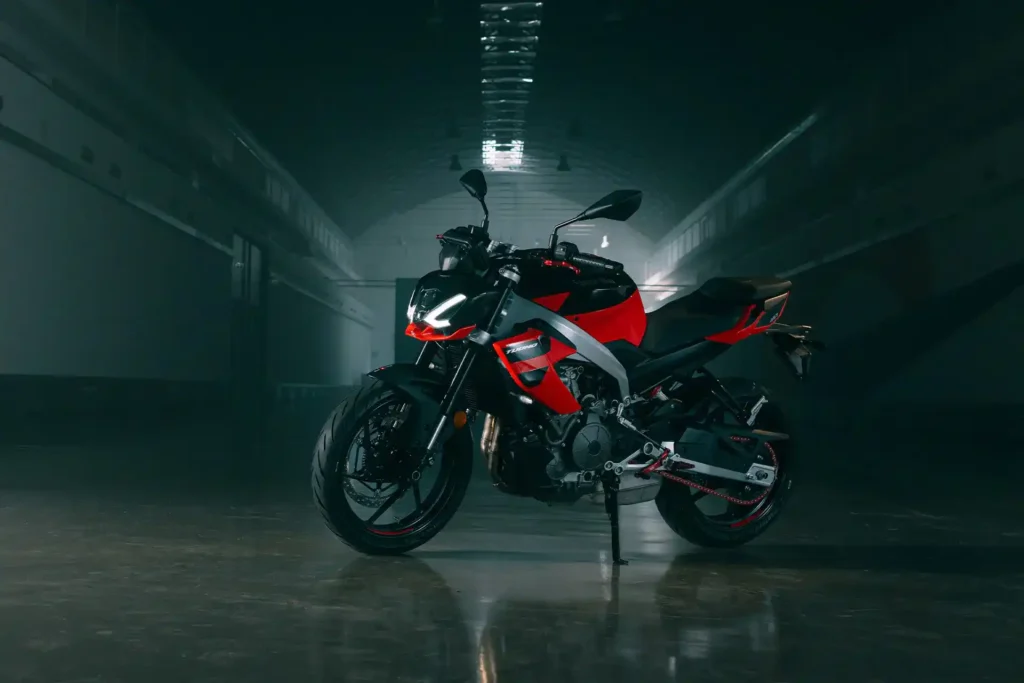 Side view of the Aprilia Tuono 457 showcasing its aggressive streetfighter design and red color variant.